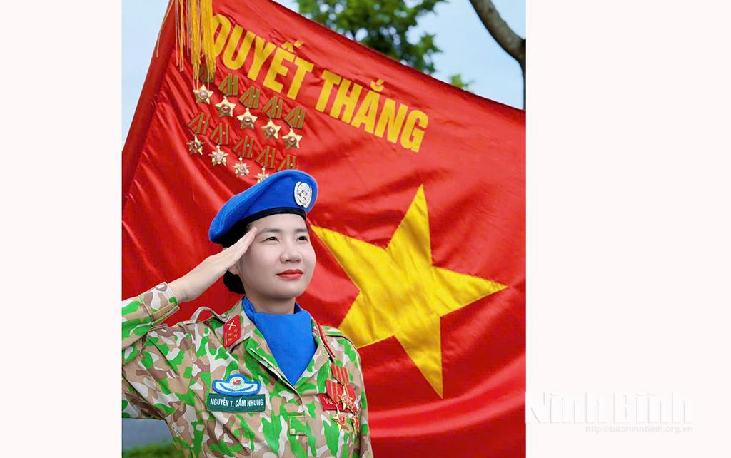 Thiếu tá chuyên nghiệp Nguyễn Thị Cẩm Nhung bên lá cờ Quyết thắng.