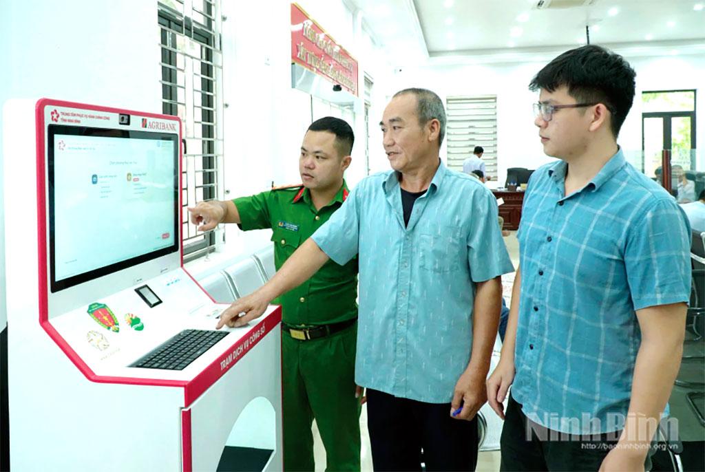 Cán bộ xã Rạng Đông hướng dẫn người dân sử dụng Kiosk hành chính công thông minh.