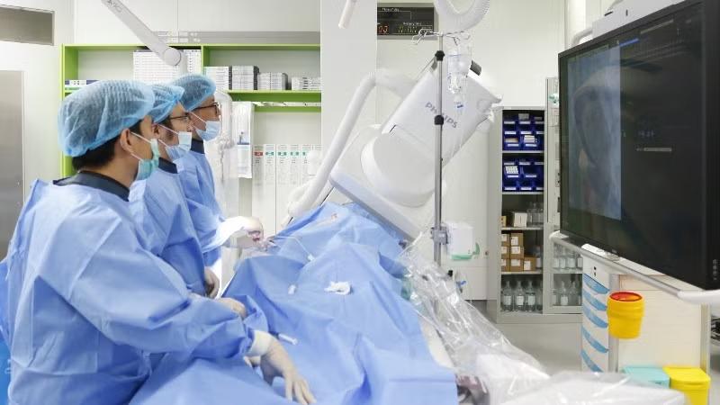 Ê kíp thực hiện kỹ thuật nút động mạch phế quản dưới hướng dẫn của hệ thống chụp mạch số hóa xóa nền.