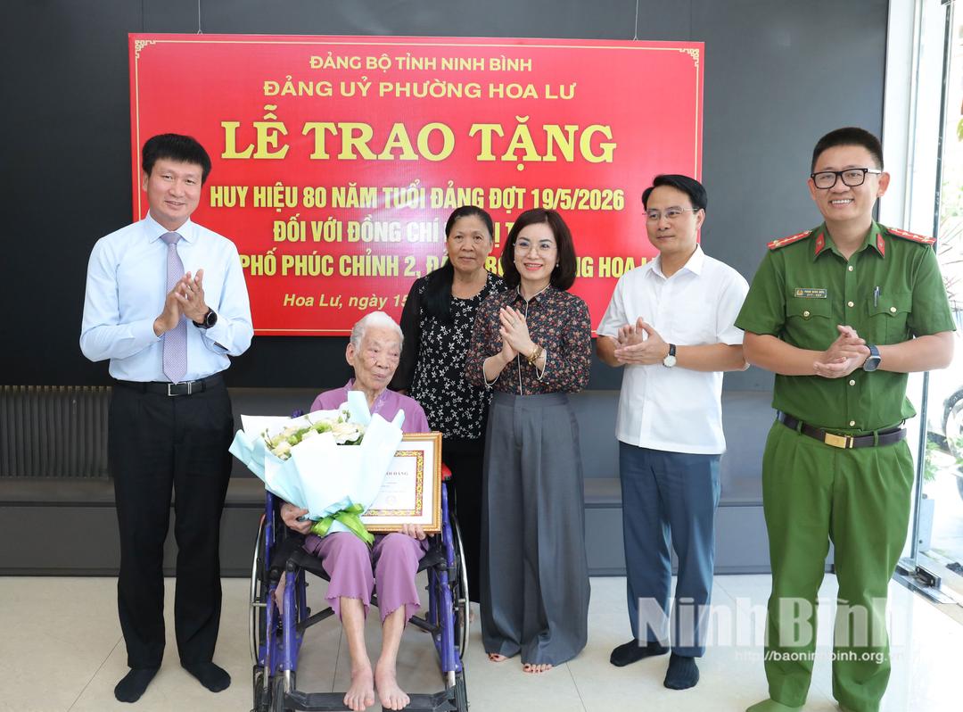 Đồng chí Trần Huy Tuấn, Ủy viên Trung ương Đảng, Bí thư Tỉnh ủy tặng hoa chúc mừng đồng chí Lê Thị Tuyết, đảng viên Chi bộ phố Phúc Chỉnh 2, Đảng bộ phường Hoa Lư.