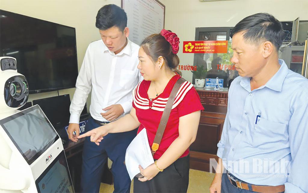 Cán bộ xã Quỹ Nhất hướng dẫn người dân sử dụng Robot AI tra cứu thủ tục hành chính. Ảnh: Bảo Yến