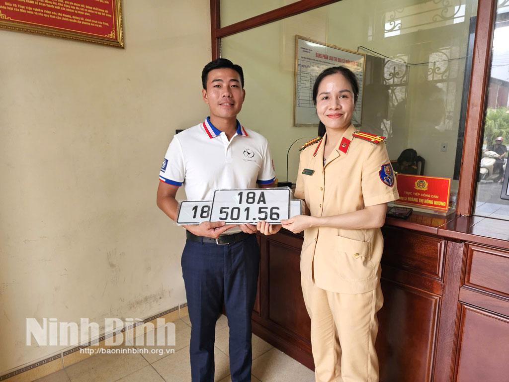 Cán bộ Phòng Cảnh sát giao thông (Công an tỉnh) trao biển số xe cho người dân tại điểm đăng ký phường Mỹ Lộc.