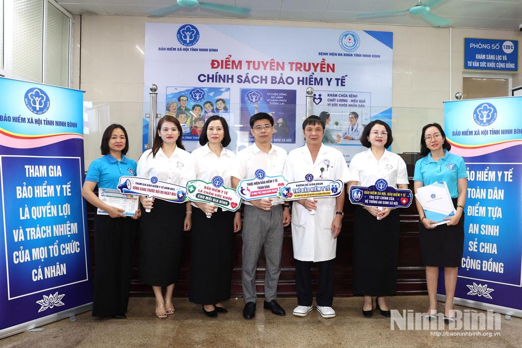 Các đại biểu chụp ảnh với các khẩu hiệu tuyên truyền về chính sách bảo hiểm y tế.