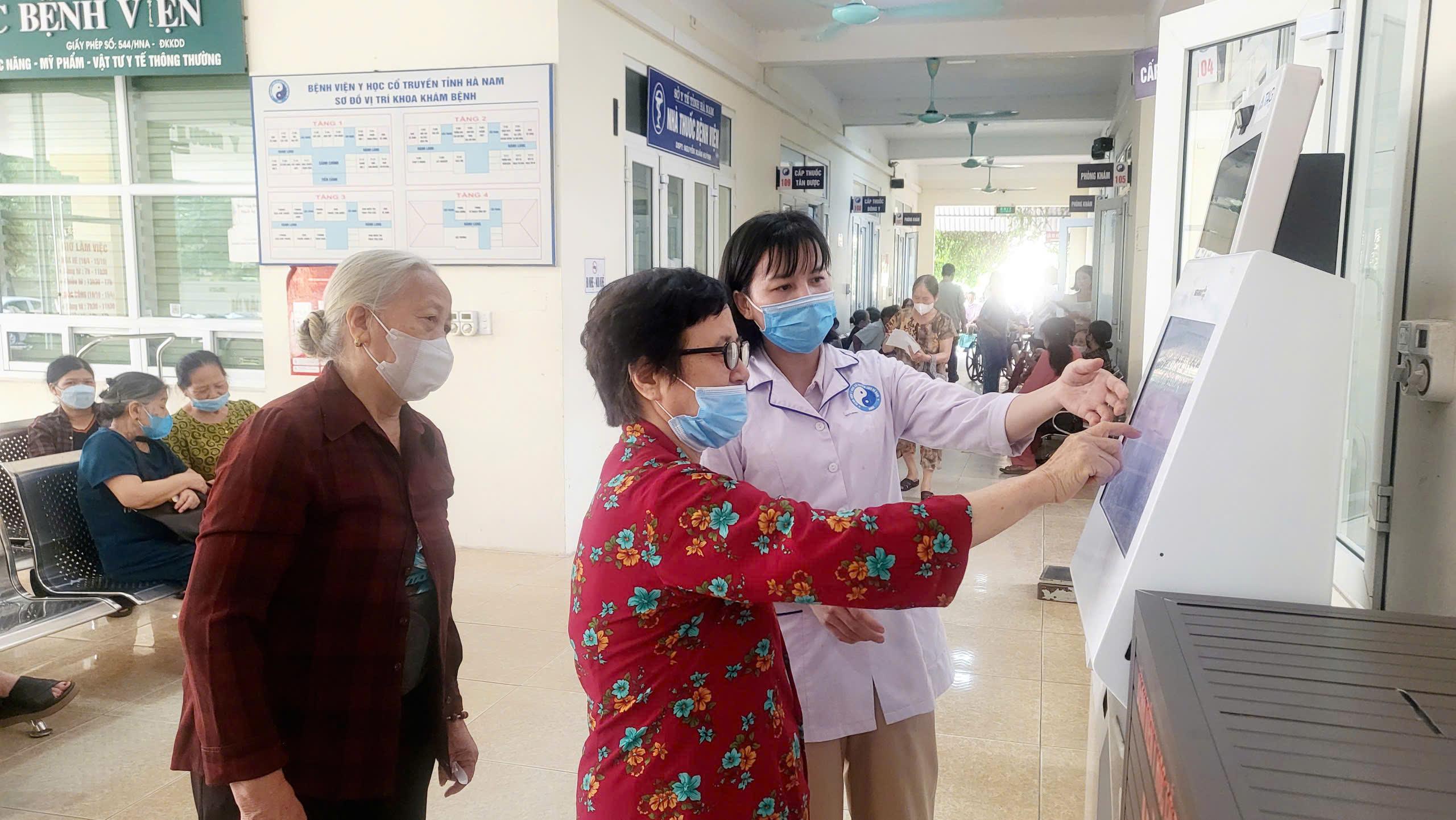 Nhân viên y tế Bệnh viện Y học cổ truyền Hà Nam hướng dẫn người dân lấy số khám bệnh tự động.