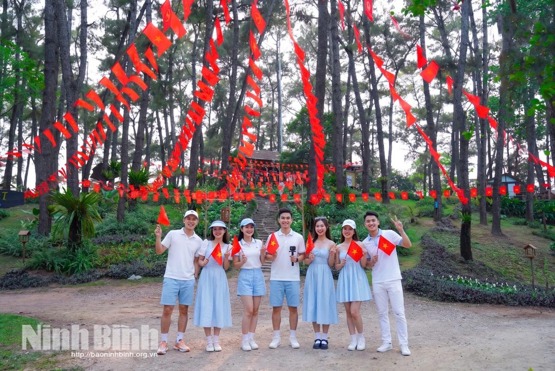 Du khách chụp ảnh với không gian rực rỡ cờ hoa tại Khu du lịch sinh thái Hồ Đồng Chương.