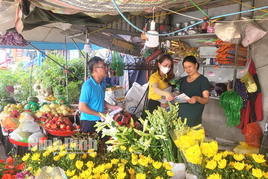 Cán bộ BHXH huyện Gia Viễn tuyên truyền các hộ kinh doanh về thực hiện chi trả trợ cấp an sinh xã hội không dùng tiền mặt. Ảnh: Bùi Diệu