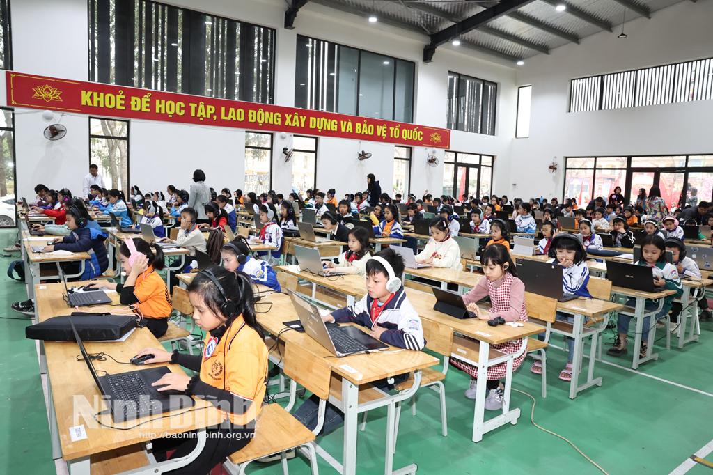 Các em học sinh tiểu học tham dự phần thi nghe, đọc, viết trên máy tính.