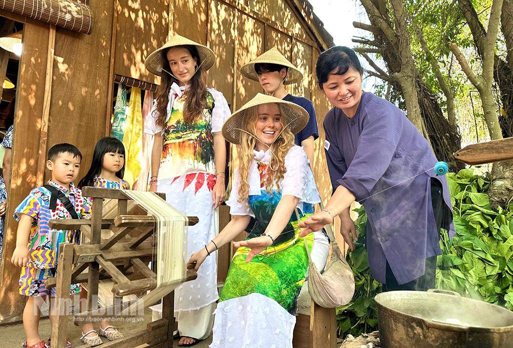 Du khách quốc tế thích thú với trải nghiệm quay tơ, dệt lụa tại Không gian trưng bày làng nghề truyền thống Ninh Bình tại bến xe Đồng Gừng (Khu du lịch Tam Cốc-Bích Động). Ảnh: Nguyễn Lựu