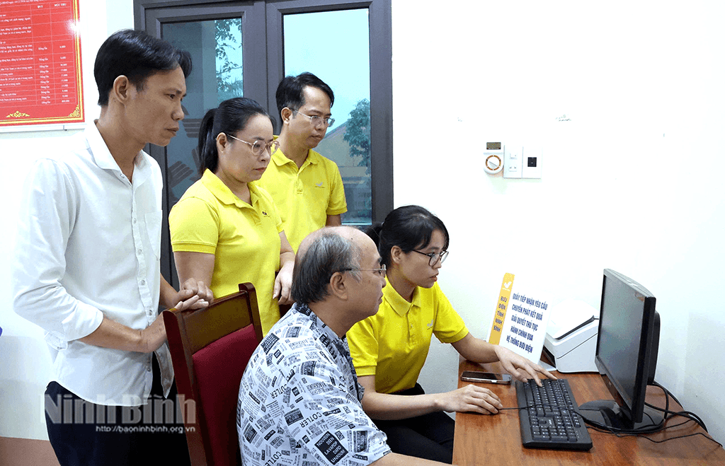 Cán bộ, nhân viên Bưu điện hướng dẫn người dân thực hiện TTHC trên môi trường điện tử. Ảnh: Minh Quang