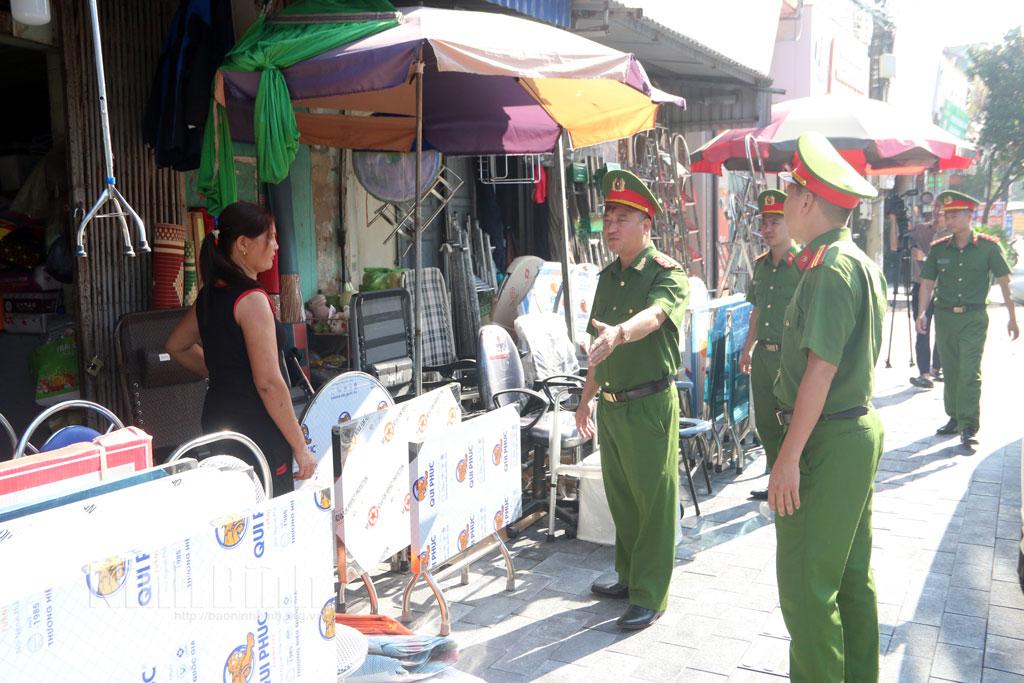 Lực lượng Công an xã tuyên truyền các hộ kinh doanh buôn bán chấp hành nghiêm quy định về bảo vệ hành lang ATGT.