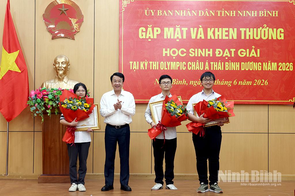 Đồng chí Nguyễn Thanh Bình, Phó Bí thư Tỉnh ủy, Chủ tịch UBND tỉnh trao Bằng khen và tặng hoa chúc mừng các em học sinh.