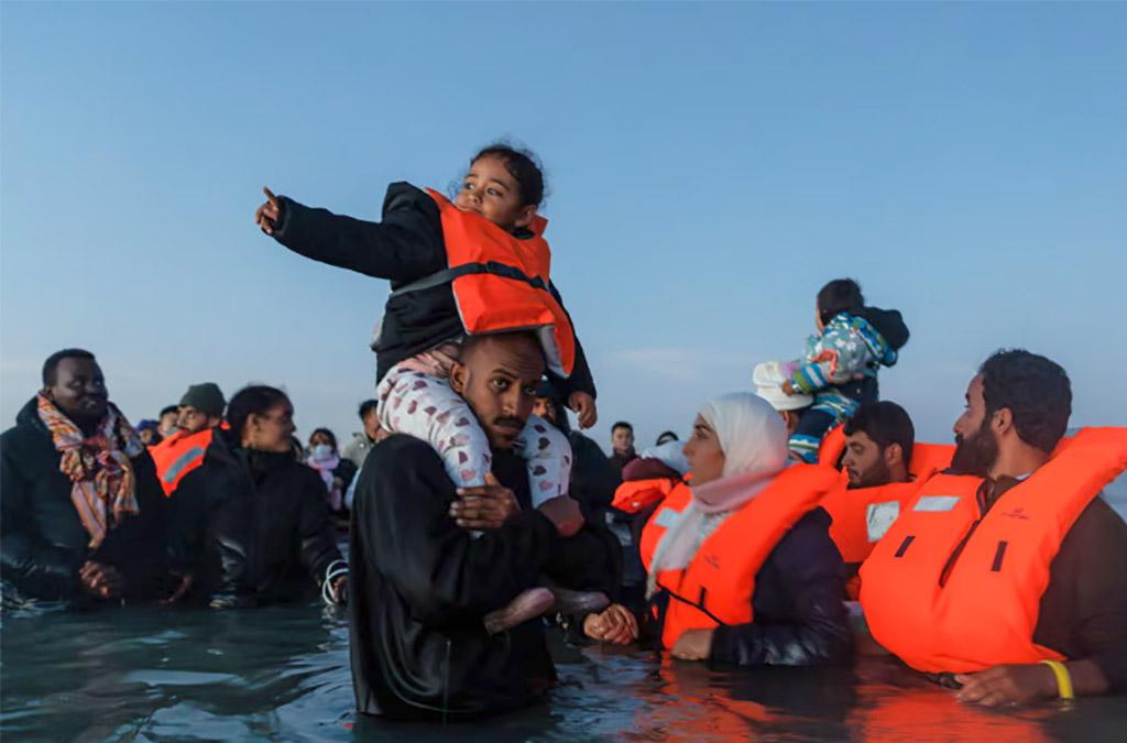 Nhiều gia đình lội trong nước biển ở phía bắc của nước Pháp để chờ thuyền nhỏ đưa họ tiến vào nước Anh. Ảnh: https://www.theguardian.com/