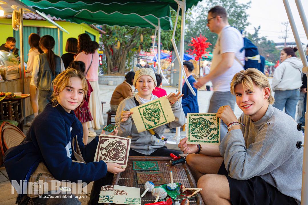 Du khách nước ngoài thích thú trải nghiệm hoạt động in dập bản tại Khu du lịch Tam Cốc - Bích Động dịp Tết Nguyên đán. Ảnh: Ngọc Linh